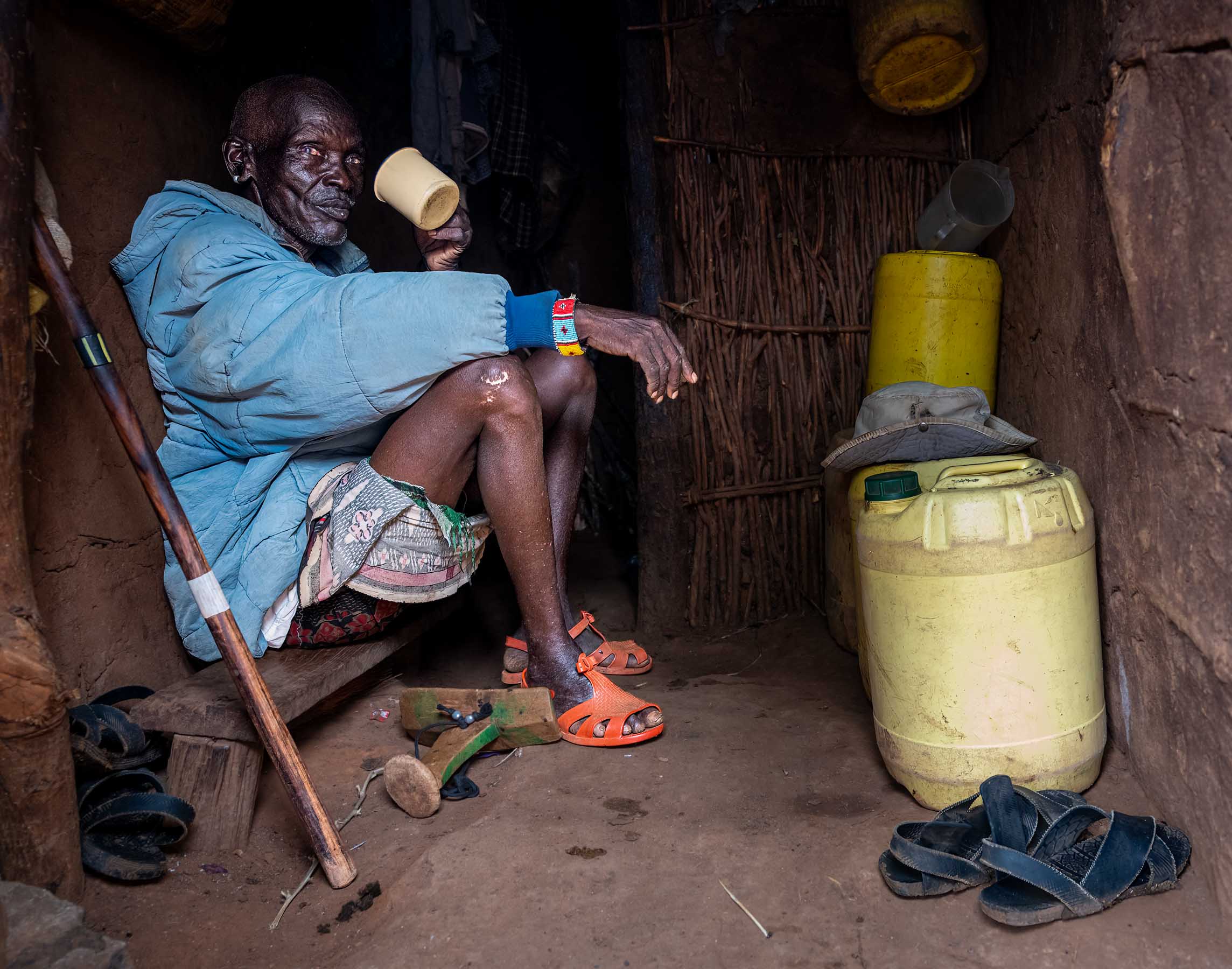Man resting inside his hut with water containers, northern Kenya