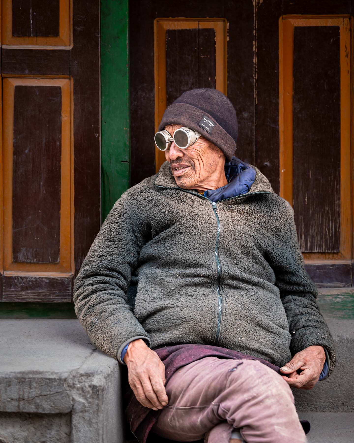 Man in dark glasses sitting outside a building, Nepal