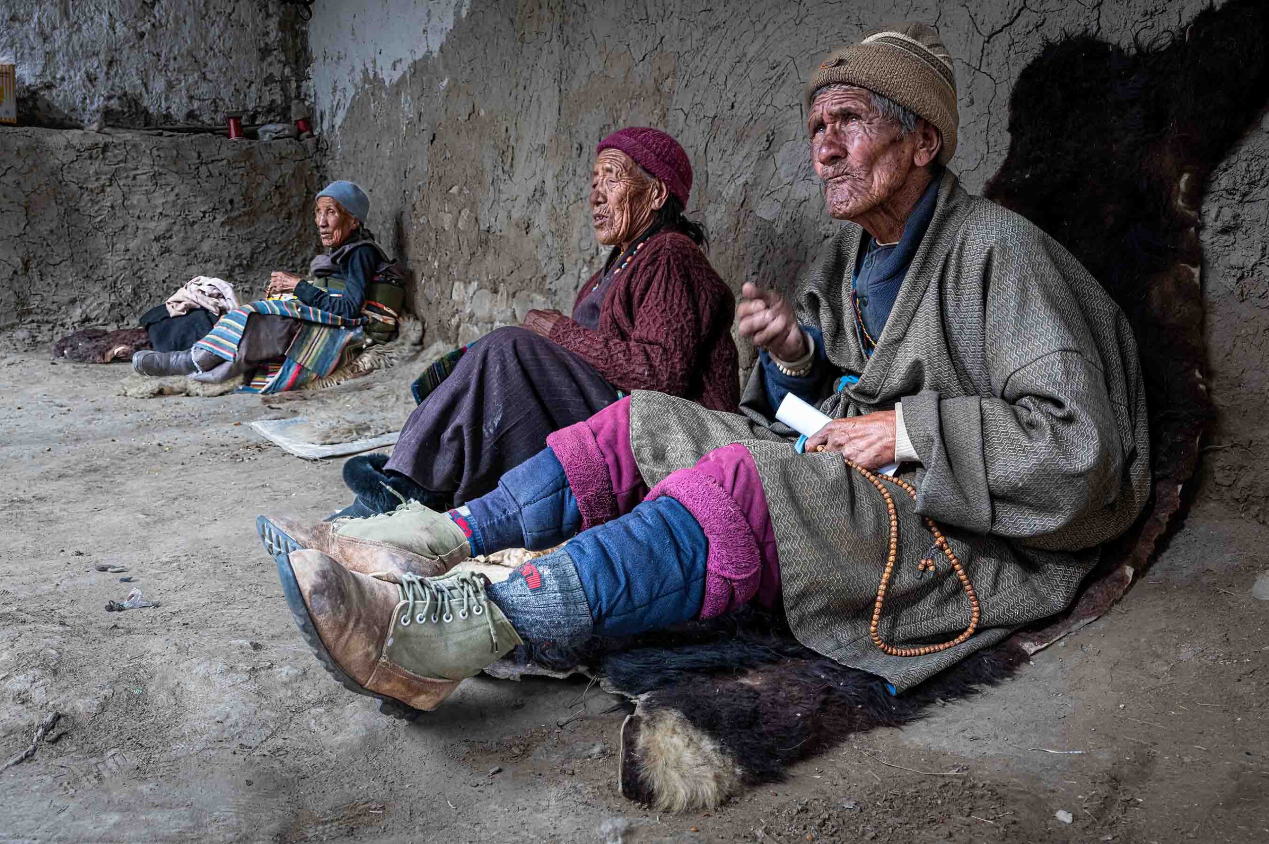 Three people resting against a wall on the trail, Mustang, Nepal