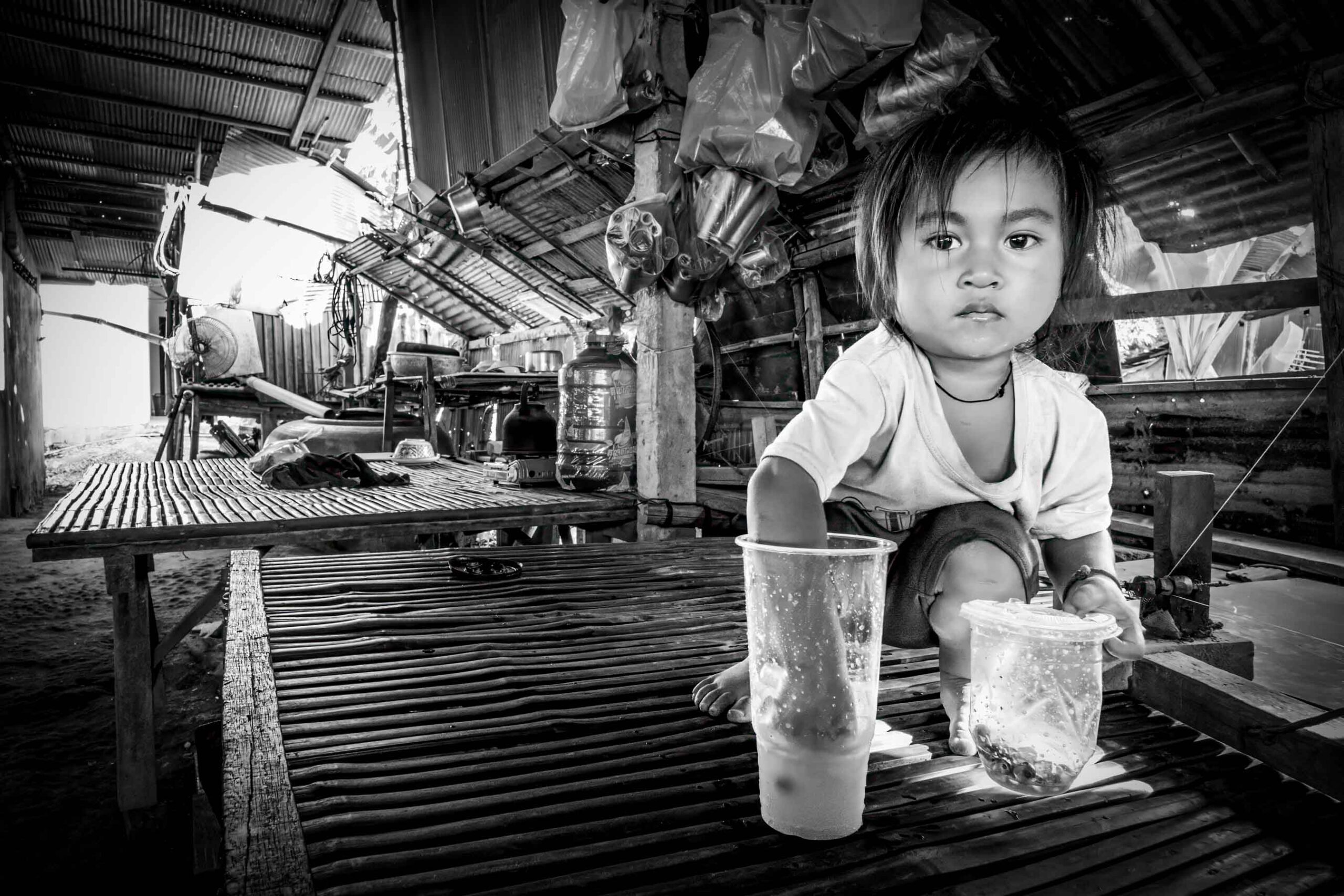 Child sitting among buckets in a workshop, Cambodia