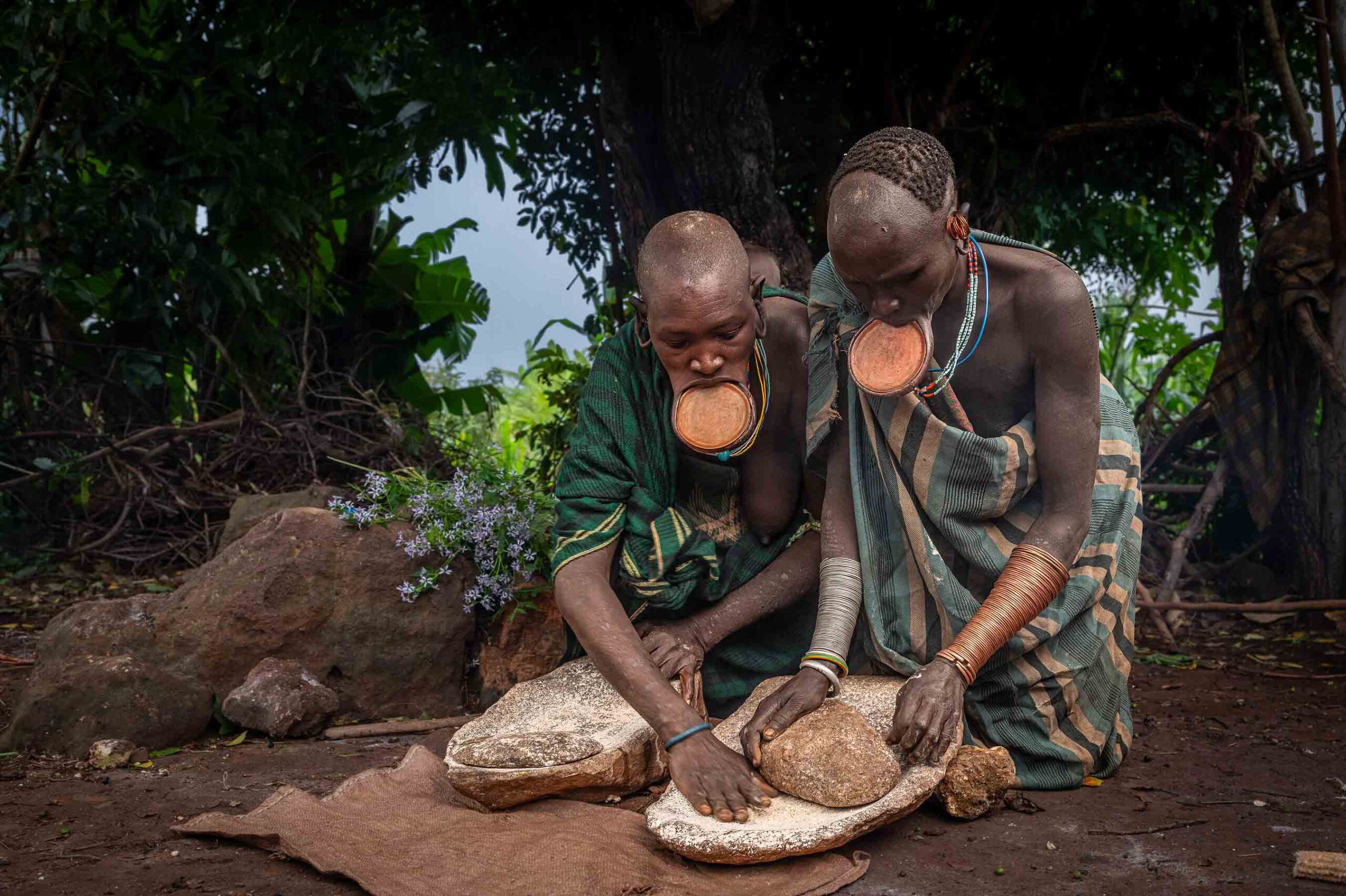 Two women grinding grain, Omo Valley, Ethiopia