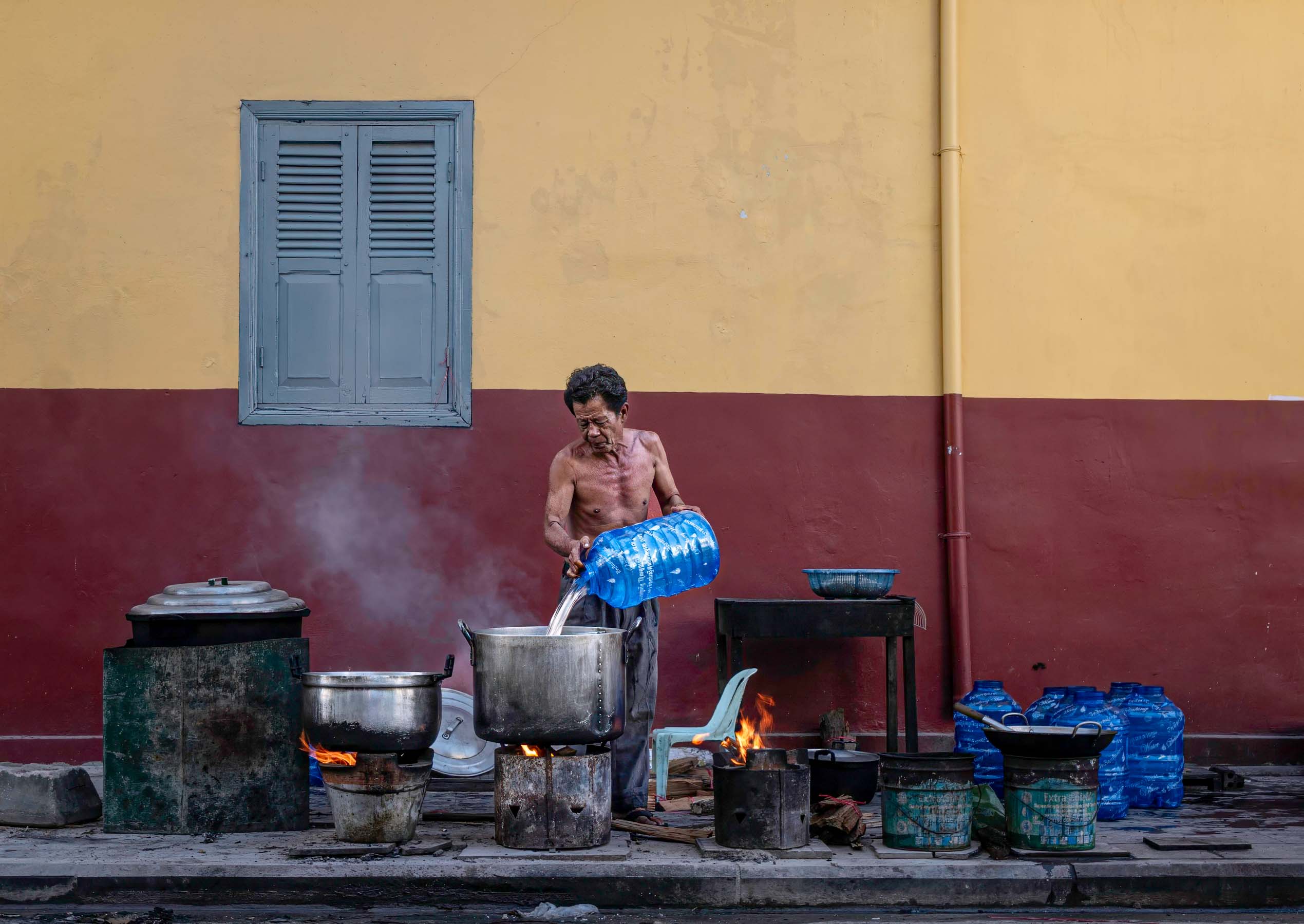 Street kitchen against a red and yellow wall, Cambodia