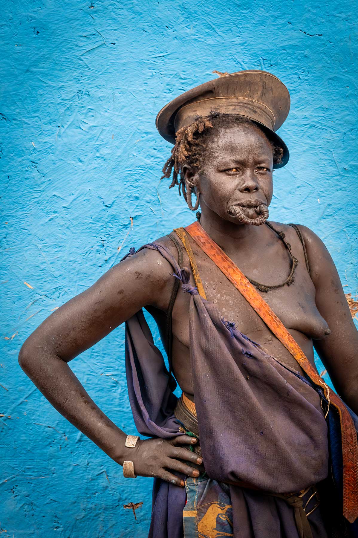 Woman standing against a blue wall, Omo Valley, Ethiopia