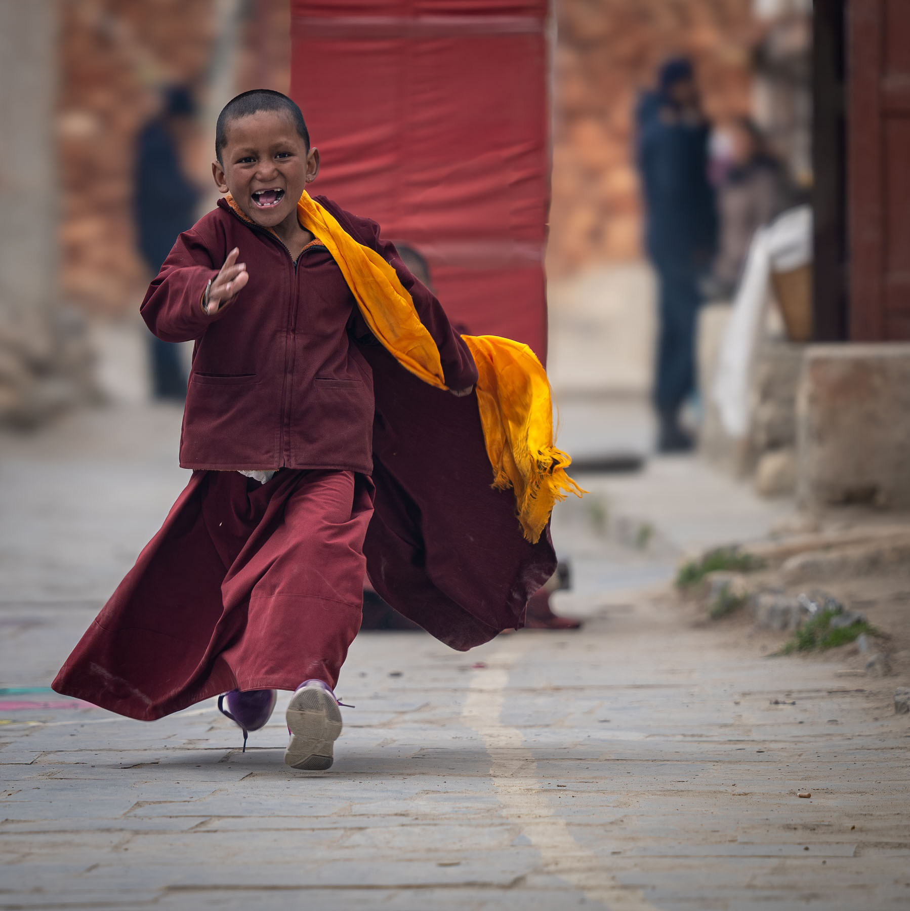 Young monk running down a street, Nepal