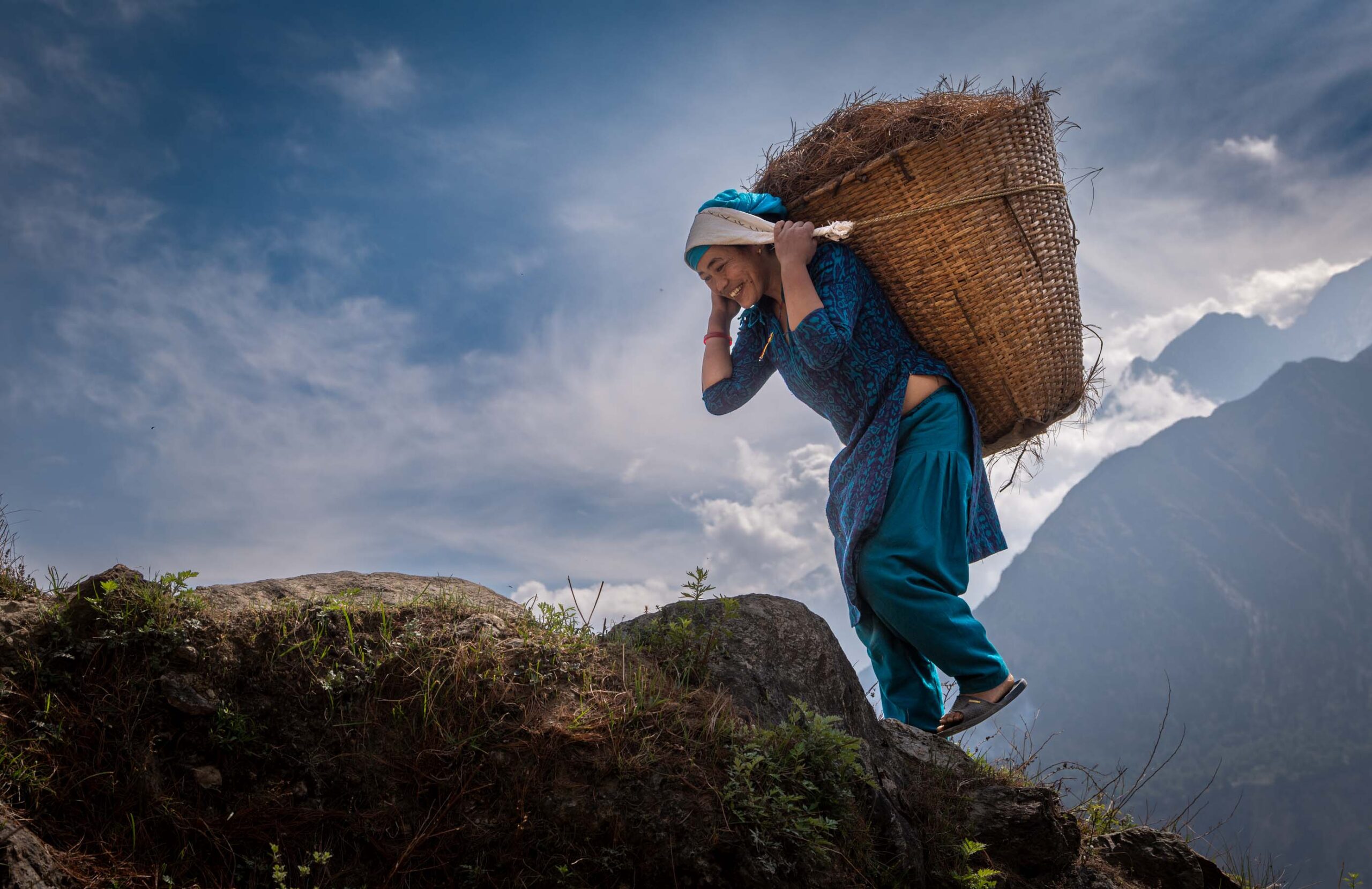 Woman carrying a large basket on a ridge, Mustang, Nepal